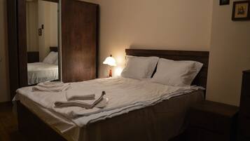 Una cama bien hecha con sábanas blancas y una lámpara al lado.