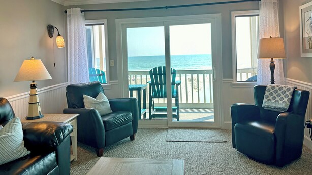 A room with a view of the ocean, featuring two leather chairs, a table, and a ceiling fan. - Surfwatch III 205 - Oceanfront Condominium in Surfside Beach (Surfside Beach)