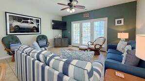 Una sala de estar con sofá, sillones, televisor y ventilador de techo.