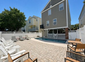 A backyard with a pool, outdoor seating, and a two-story house. - Fenway Park - Second Row in Surfside Beach (Surfside Beach)