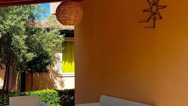 A covered outdoor seating area with wicker furniture and a hanging light fixture.