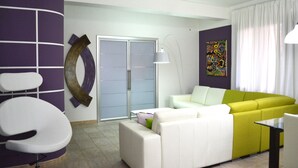 A modern living room with a white and yellow sofa, a white armchair, a glass table, and a large abstract painting on the wall.