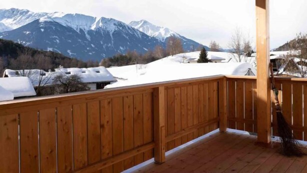 Ein hölzerner Balkon mit Blick auf schneebedeckte Berge.