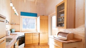 Eine kompakte Küche mit Holzausstattung, einem Fenster und einer eingebauten Mikrowelle.
