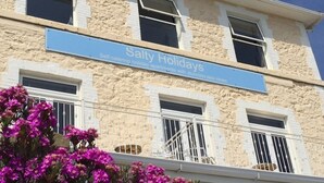 A building with a sign reading "Salty Holidays" advertising self-catering holiday apartments with stunning sea views. - Great location, close to Ventnor beach and town. Perfect for families. (Isle of Wight)