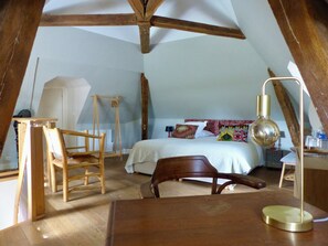 A bedroom with a sloped ceiling, wooden furniture, a bed with patterned bedding, and a bedside lamp. - The commandery of the castle, at the gates of Chambord (Huisseau-sur-Cosson)
