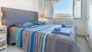 Een slaapkamer met een groot bed, een nachtkastje, een dressoir en een raam met uitzicht.