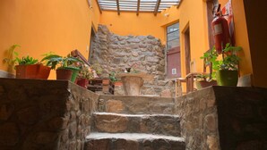 A stone staircase leading to a room with a skylight, surrounded by potted plants and a stone wall. - Hostal Casa De Piedra (Humahuaca)