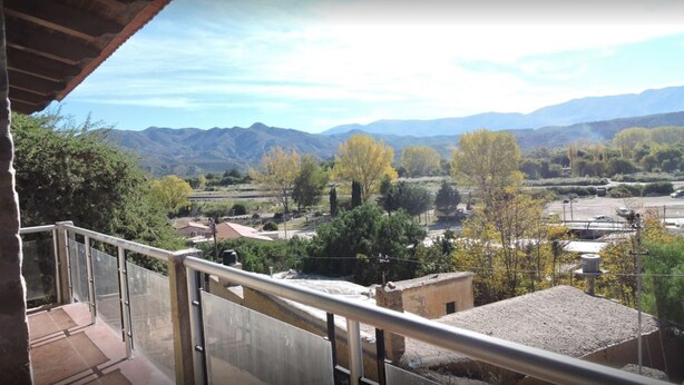 A balcony with a view of a valley, mountains, and trees. - Hostal Casa De Piedra (Humahuaca)