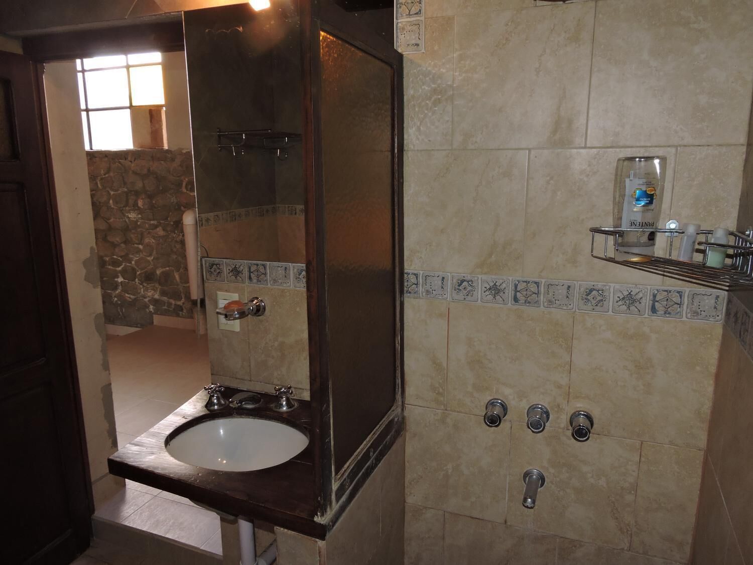 A bathroom with a large mirror, a sink, and a shower area.