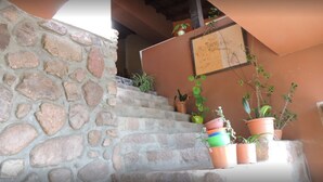 A stone staircase leading to a wooden door, with potted plants on the landing. - Hostal Casa De Piedra (Humahuaca)
