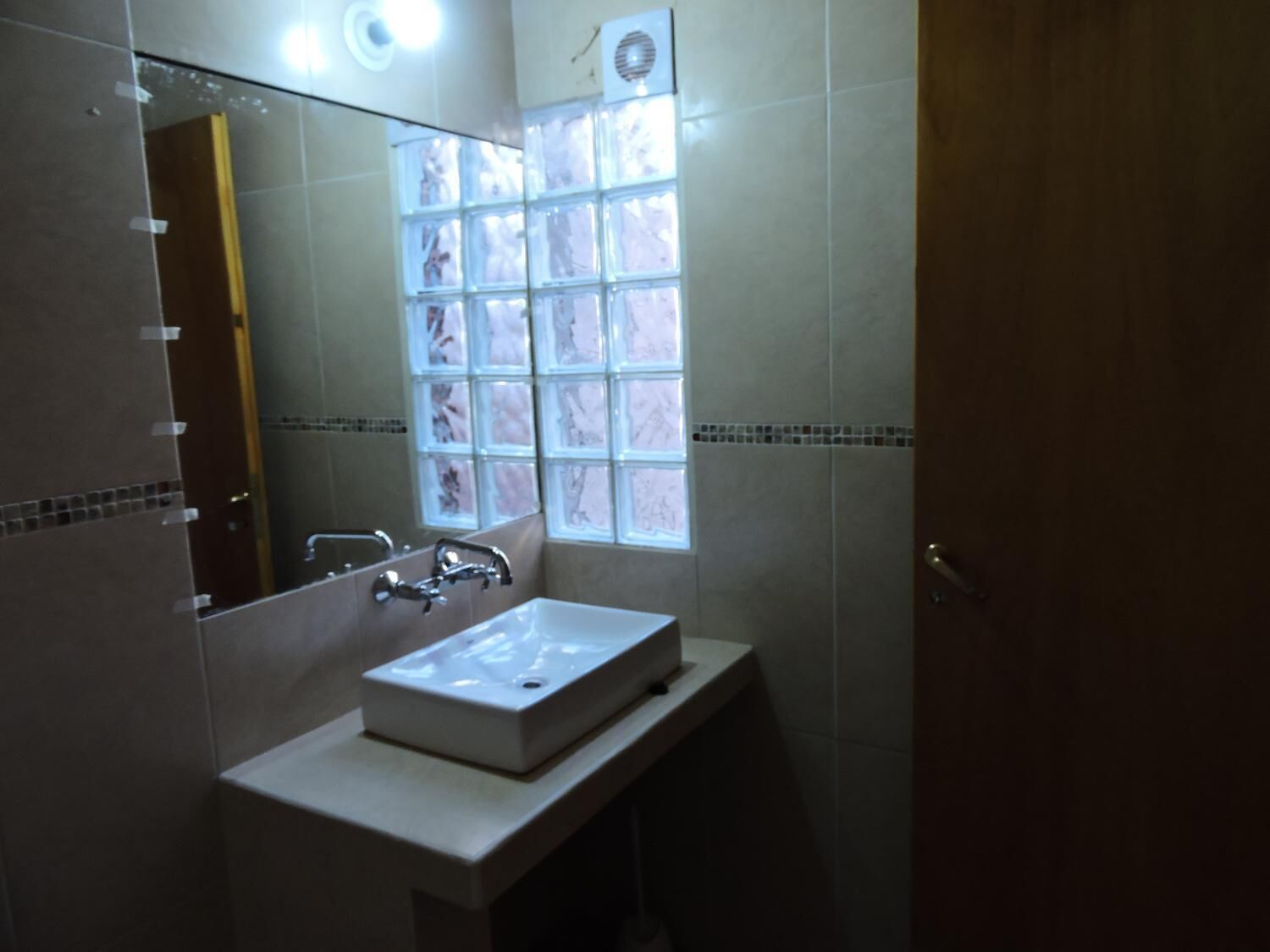 Un baño con un espejo grande, un lavamanos y una ventana.