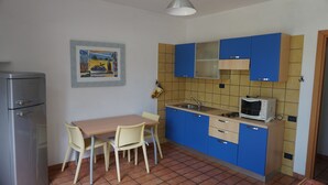 Une cuisine de taille réduite avec des meubles bleus, une petite table à manger et un réfrigérateur.
