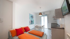 Una sala de estar moderna con sofá, mesa de comedor y zona de cocina.