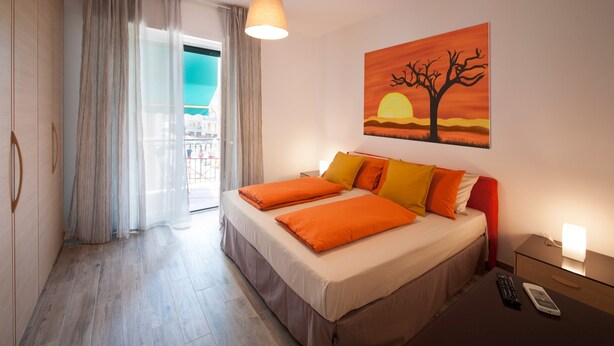 Habitación de hotel con cama, mesita de noche, un cuadro y vistas de la ciudad.