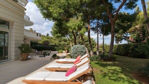 Een zonnig terras met lounge fauteuils.
