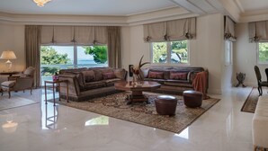 Een ruime woonkamer met een grote bank, een bijzettafeltje en een kroonluchter.