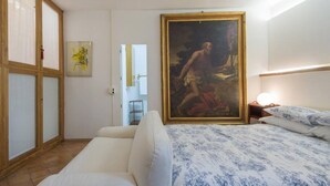 Une chambre à coucher avec un lit, un tableau, une fenêtre et une porte.