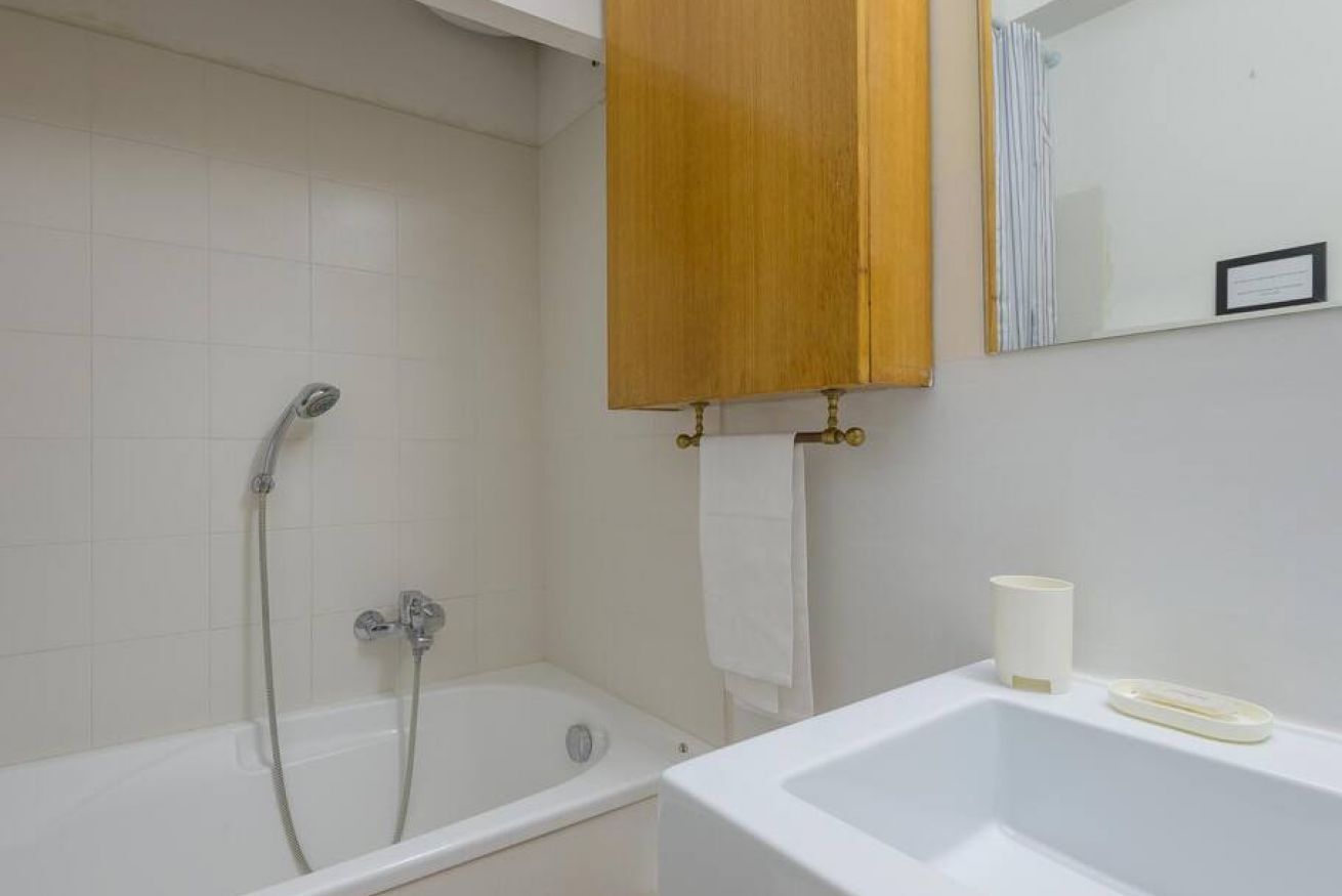 A bathroom with a bathtub, a shower, a sink, and a wooden cabinet above the sink.