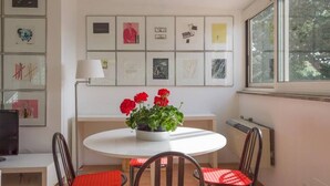 Un coin repas avec une table ronde, des chaises, une plante en pot et des œuvres d’art encadrées accrochées au mur.