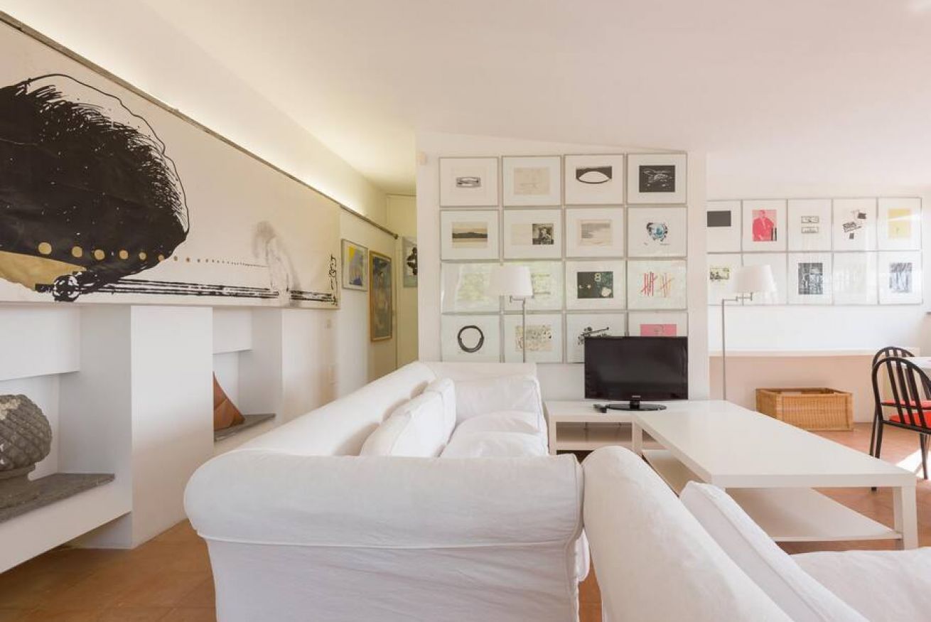Ein modernes Wohnzimmer mit einer Couch, einem Fernseher und einer Wand mit gerahmten Bildern.