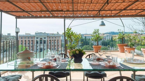 Une table dressée pour le dîner, avec en arrière-plan la vue sur des bâtiments.