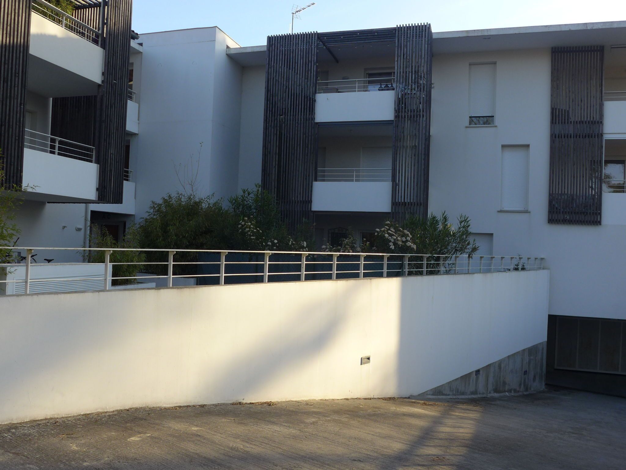 Un bâtiment moderne doté de balcons, d’une façade blanche et d’une clôture en métal.