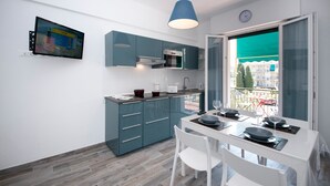 Una cocina moderna con armarios verde azulado, un microondas y un comedor con una mesa preparada para dos.