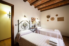 Ein Zimmer mit zwei Betten, einem kleinen Tisch mit Lampe und Wanddekorationen.