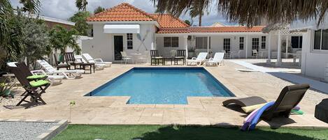 Un espace piscine comprenant des chaises longues, une petite piscine et un bâtiment doté d’un toit en tuiles.