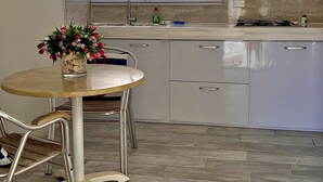 A kitchen with a round table, a sink, and a window with blinds. - Tu Casita en Aruba (CRISTINA KING) (Noord)