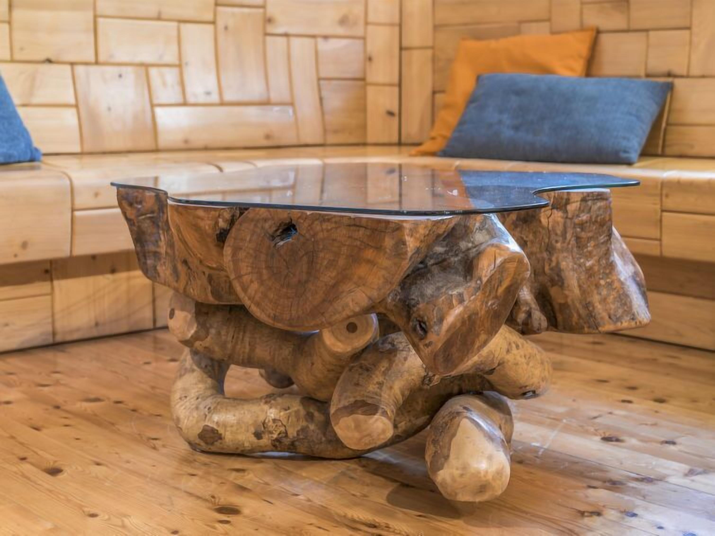 A round wooden coffee table with a glass top, placed on a wooden floor.