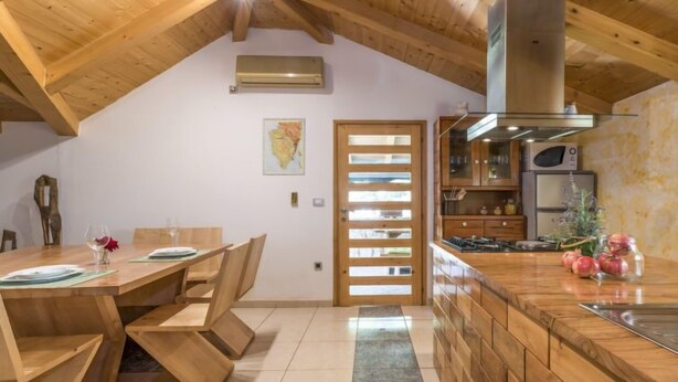 Una cocina moderna con vigas de madera, un comedor con mesa y sillas de madera, y una isla de cocina con un fregadero.