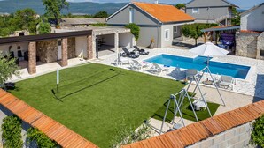 Una propiedad residencial con piscina, cancha de tenis y zona de patio de piedra.