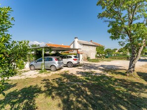 Guesthouse surrounded by lush greenery, with a tiled roof and a prominent tree.