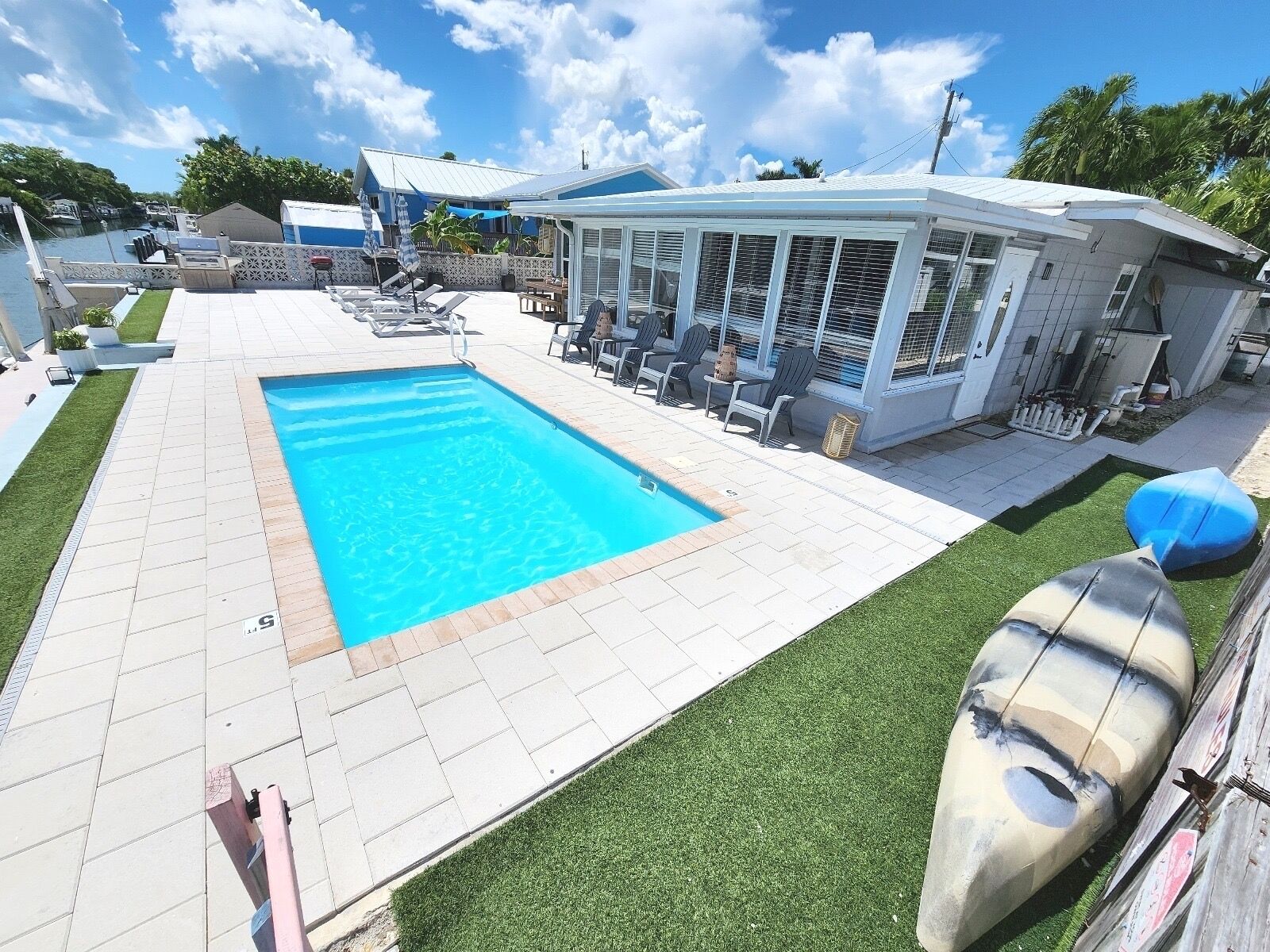 A swimming pool with a sunshade, lounge chairs, and a covered seating area.