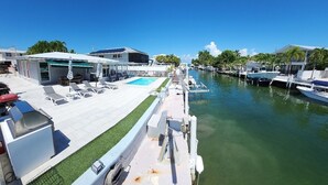 A marina with boats docked, a swimming pool, and a covered area with lounge chairs. - Yellowtail Getaway 3 bedrooms,4 beds,3 bath,boat dock,ice maker and heated pool (Marathon)