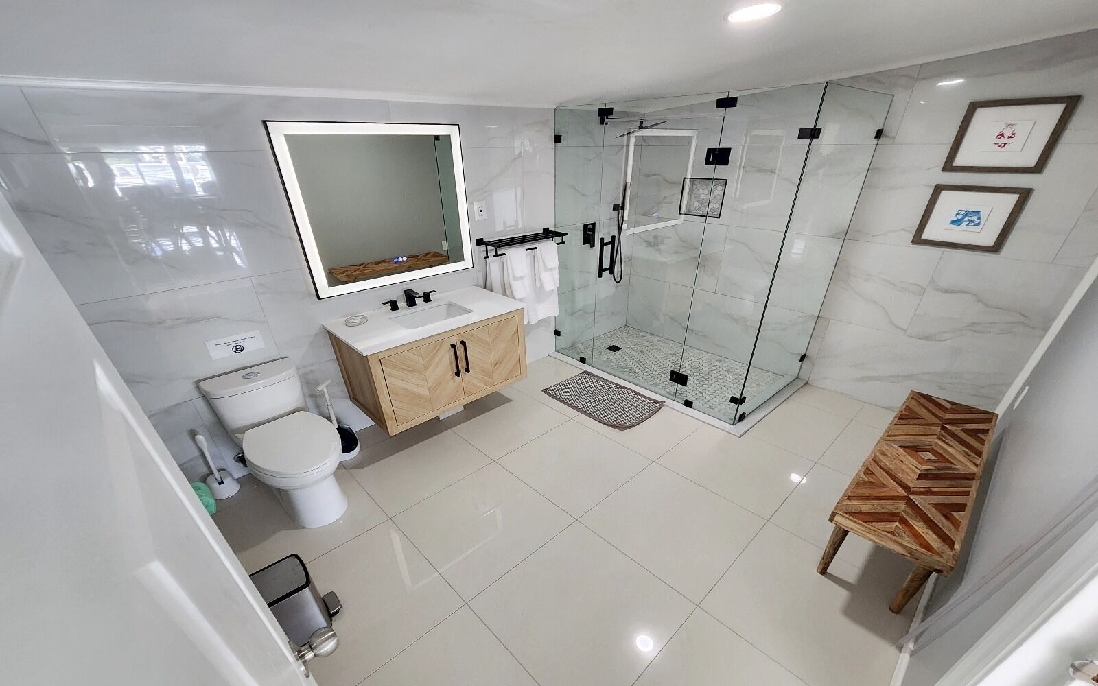 Un baño moderno con ducha de vidrio, inodoro, lavabo con espejo y tocador de madera.
