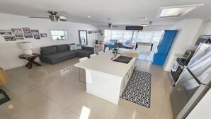 A modern kitchen with a central island, a dining area with blue chairs, and a grey sofa. - Yellowtail Getaway 3 bedrooms,4 beds,3 bath,boat dock,ice maker and heated pool (Marathon)