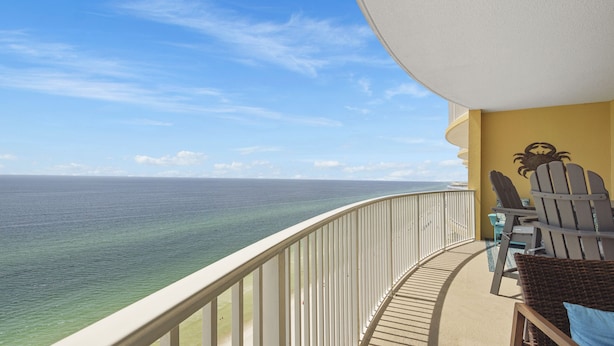 Een balkon met uitzicht op de oceaan, een gele muur met een krabversiering en twee Adirondack-stoelen.