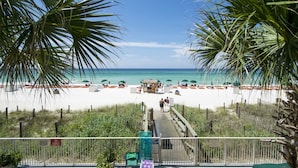 Uitzicht op een strand met palmbomen, een zandstrand en enkele parasols.