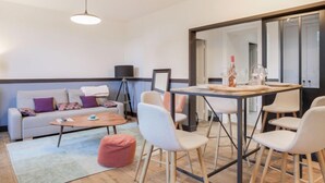 A modern living room with a sofa, coffee table, and chairs, a dining table with chairs, and a large mirror. - Ker Louis by Interhome (Dinard)