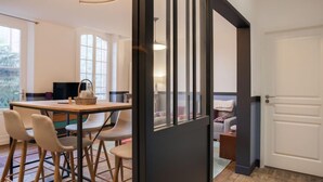 A modern kitchen with a dining area, wooden stools, and a large window. - Ker Louis by Interhome (Dinard)