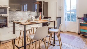 A modern kitchen with a central island, bar stools, and a dining table. - Ker Louis by Interhome (Dinard)