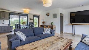 A modern living room with a grey sofa, a wooden coffee table, and a TV mounted on the wall. - L'Oliveraie by Interhome (Pernes les Fontaines)