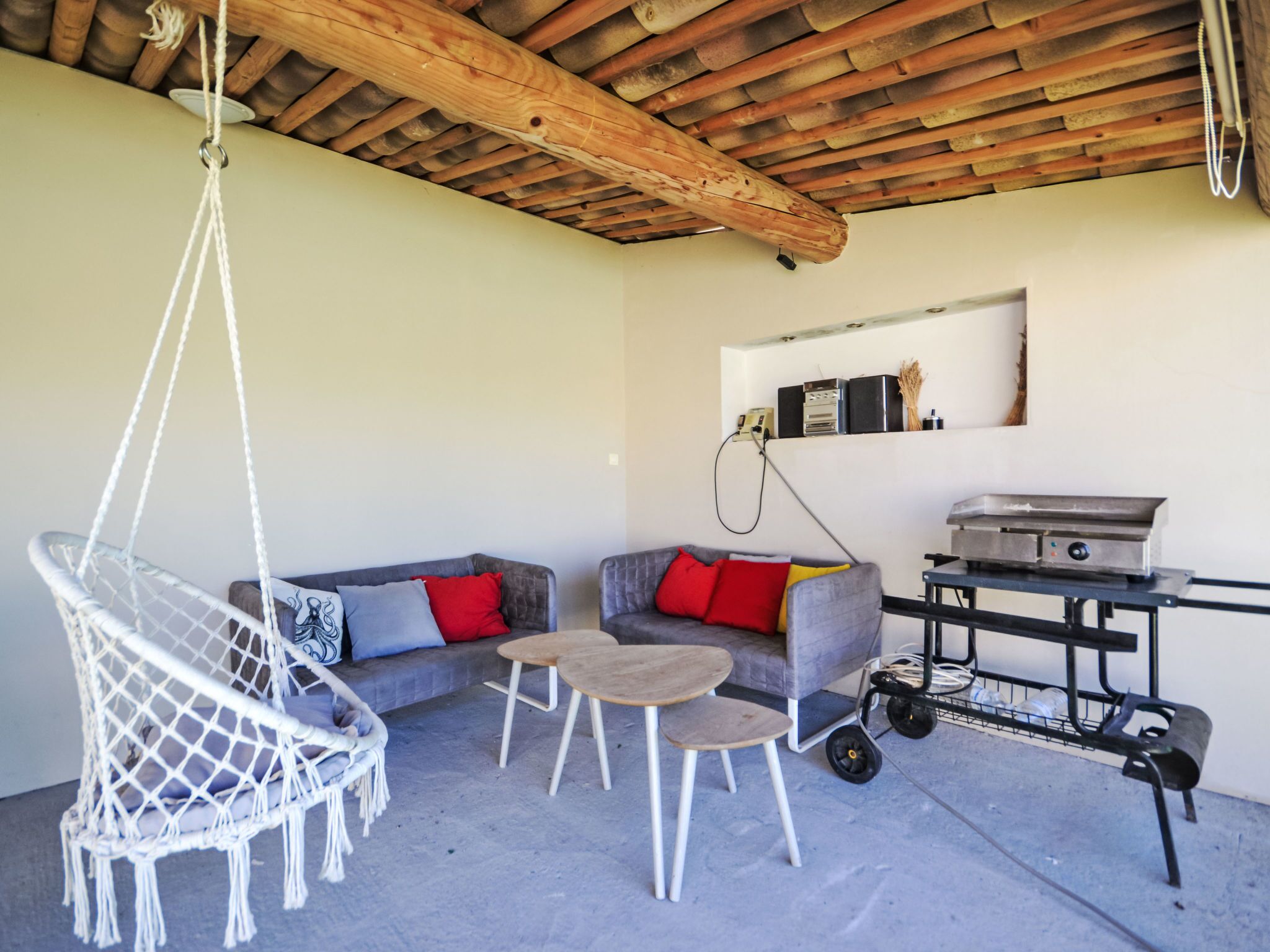 A modern outdoor seating area with a hanging chair, two sofas, and a small table.