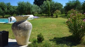 A large stone planter in a garden with a pool and trees in the background. - L'Oliveraie by Interhome (Pernes les Fontaines)