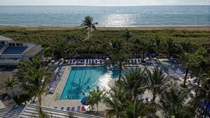 A pool area with lounge chairs, a swimming pool, and a view of the ocean. - Ocean View! Closest to golf, pool, beach, Tennis!  Clean, Owner managed (Fort Pierce)