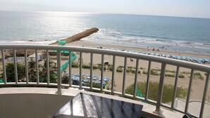 A balcony with a view of a beach, including a sandy shore, ocean, and umbrellas. - Apartament w/ Sea View in Palmetto - Bocagrande Cartagena (Cartagena)