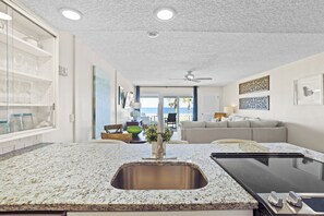 Enjoy cooking in this well-equipped kitchen with a granite countertop and stainless steel sink, offering a view of the outdoors through a large window.